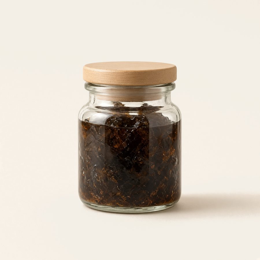 A small glass jar of dark resin with a wood lid